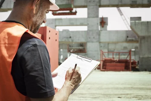 site inspection consulting services - worker with clipboard at construction site.