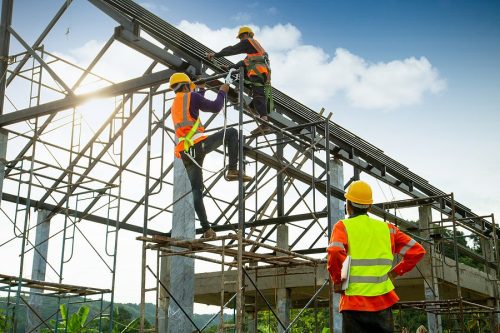 Qualified person for site safety in New York overseeing work on a metal structure with safety harnesses.