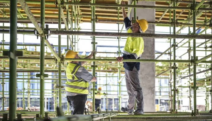 Scaffolding permits - workers on scaffolding structure at construction site.