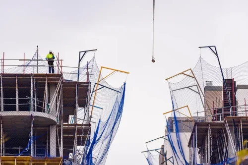 Construction equipment permit NYC - workers on elevated platforms with crane hook.